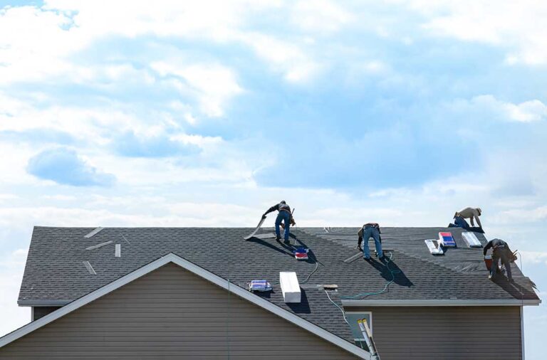 Homeowner reviewing roof warranty papers beside photos of shingles and a leaking ceiling stain.