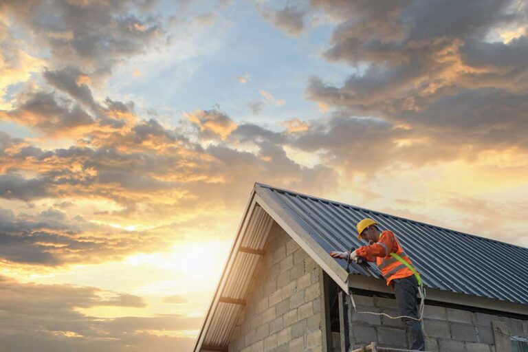 A masked roofing worker examines a damaged roof while a homeowner documents a ceiling leak from indoors.